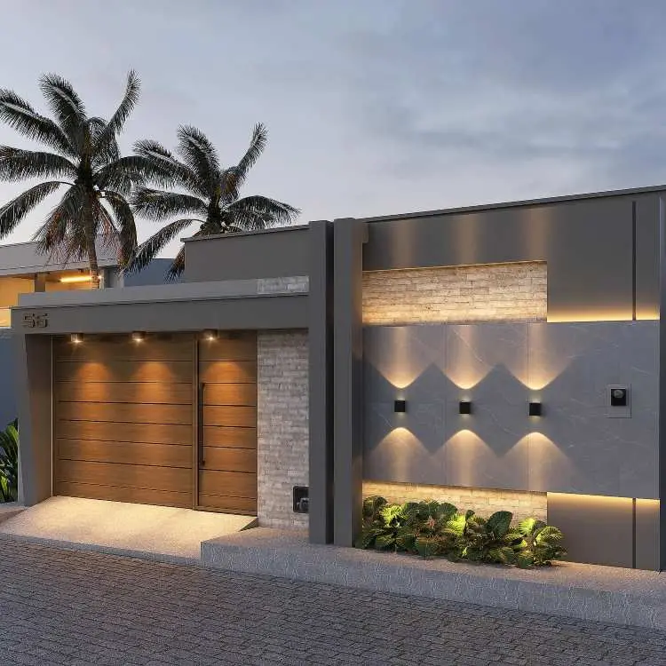 Fachada residencial com muro moderno simples com portão em madeira iluminado, detalhes em pedra clara e parede cinza texturizada com iluminação embutida. Paisagismo com plantas verdes na base, número "55" metálico e coqueiros ao fundo, sob céu azul ao entardecer.