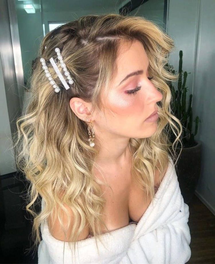 Mulher de pele clara usando cabelo loiro solto com presilhas de pérola