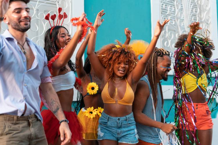 Pessoas de diversas cores de pele e estilos fantasiadas curtindo o Carnaval.