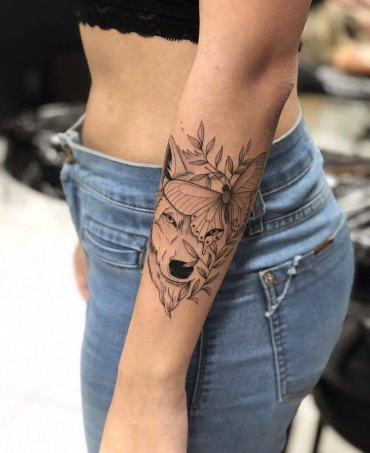 Tatuagem de lobo e borboleta no braço perto do cotovelo