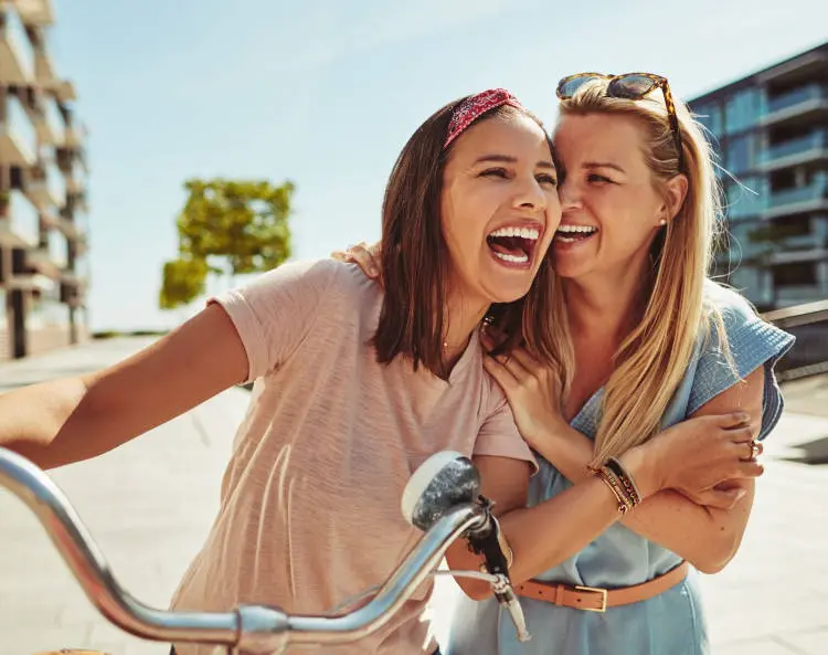 Foto de duas mulheres de pele clara rindo juntas 