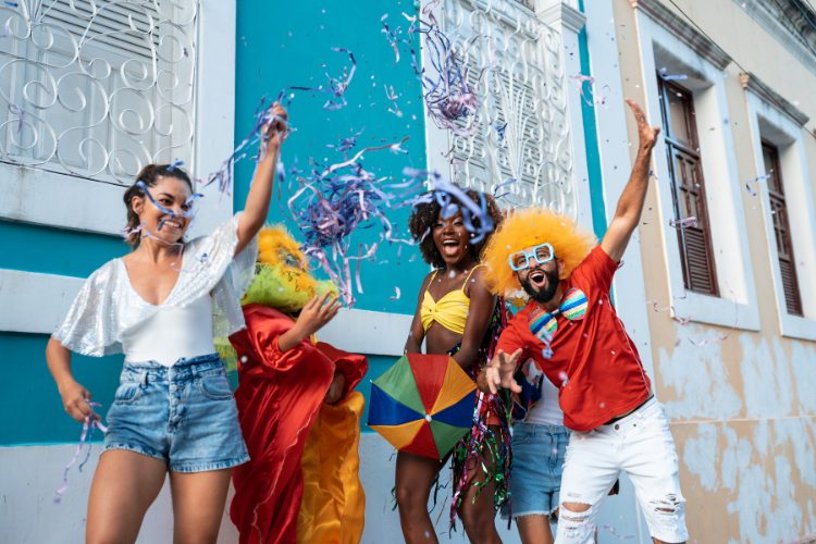 Grupo de amigos curtindo o carnaval com confete e serpentina em frente a um casarão azul