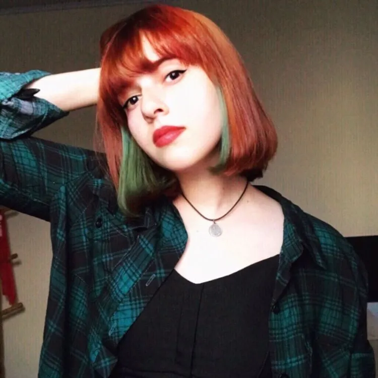 Mulher de pele clara com cabelo chanel ruivo e verde