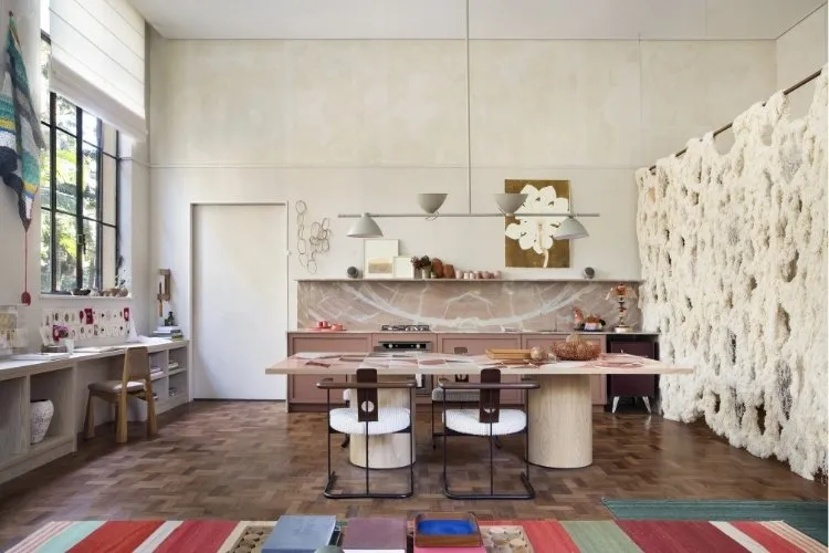 Loft com paredes e móveis em tons de off white com piso de taco de madeira e tapete colorido