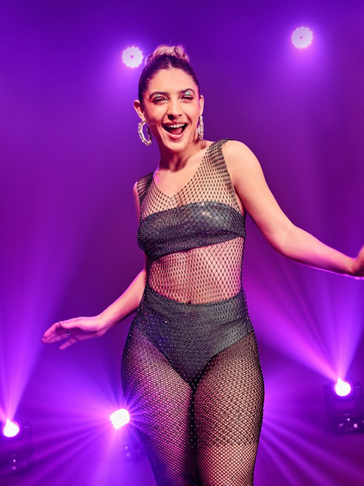 Modelo de pele clara com conjunto de top sem alça e hot pant metalizados com vestido de cristais