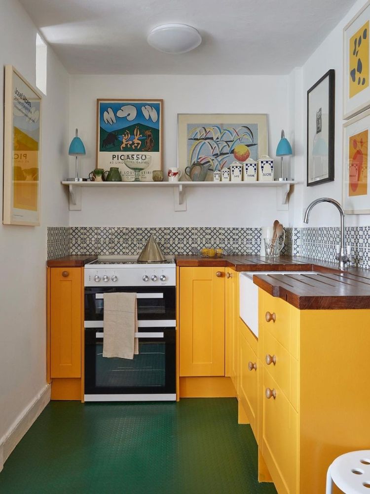 Cozinha colorida com piso verde, armários amarelos, azulejos e decorações