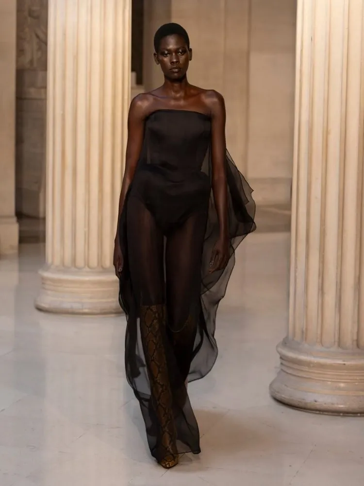 Foto de modelo negra usando vestido preto transparente na Paris Fashion Week