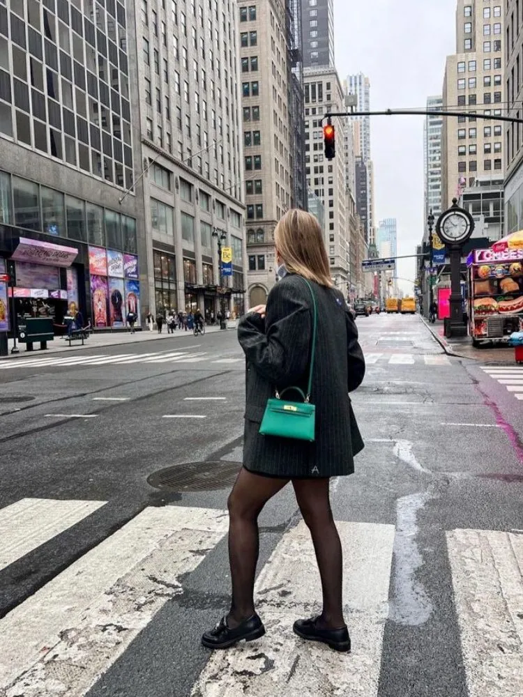 Mulher usando mocassim com blazer e meia-calça