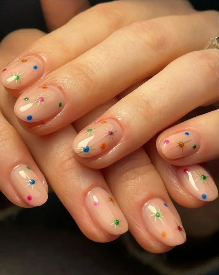 unhas curtas redondas decoradas com desenhos de estrelas coloridas para fim de ano