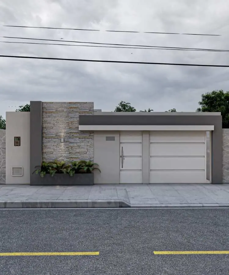 Fachada de casa contemporânea com muro moderno simples em tons bege e cinza. Portão e porta brancos com linhas horizontais. Parede lateral revestida com pedra iluminada, paisagismo com plantas na base, calçada pavimentada e céu nublado ao fundo.