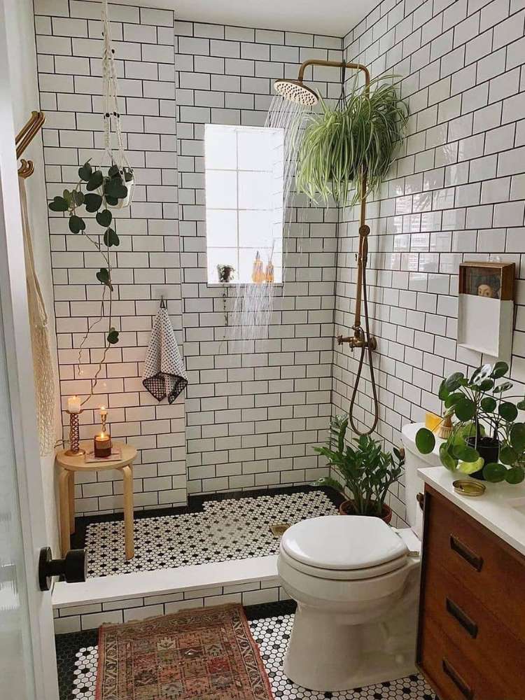 Banheiro de azulejo branco que imita tijolos, com box sem vidro, vaso sanitário, pia e plantas distribuídas