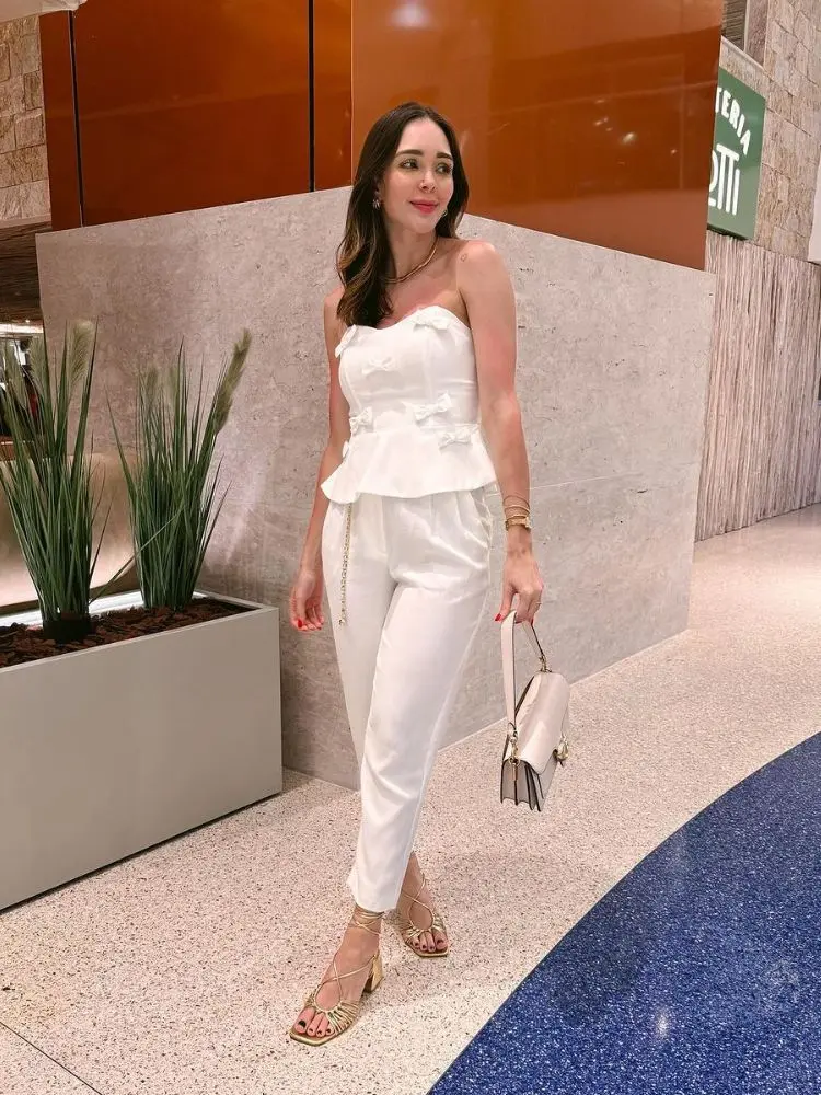 Gio Vargas usando blusa sem alça, calça branca e sandália dourada para o Ano Novo