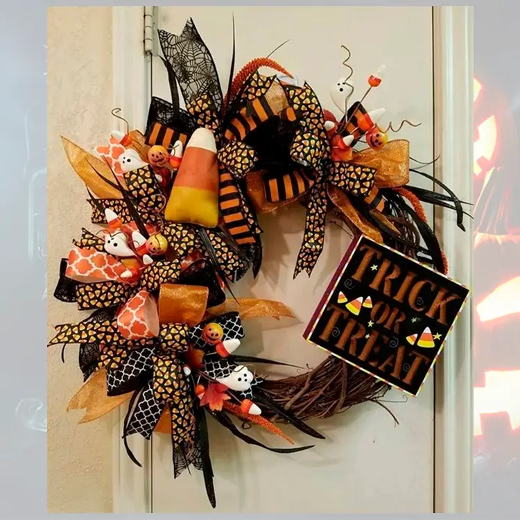 Foto de porta decorada com guirlanda de laços de Dia das Bruxas em tons de laranja, com fantasmas e quadro escrito "trick or treat"