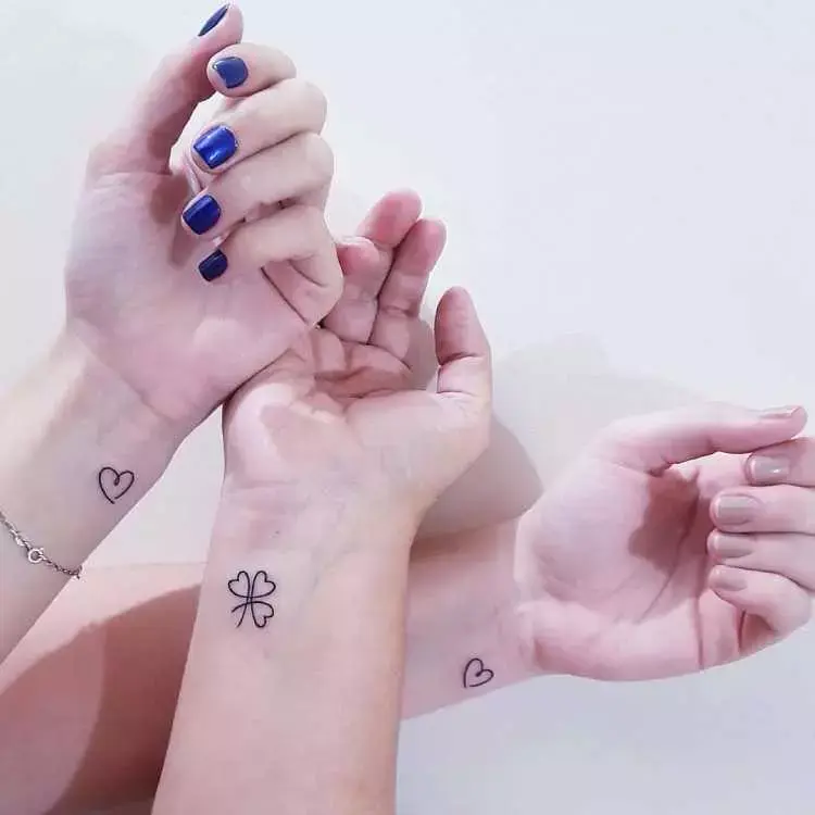 3  pessoas de pele clara com pulso tatuado, sendo duas delas com um coração e uma com trevo de 3 folhas 