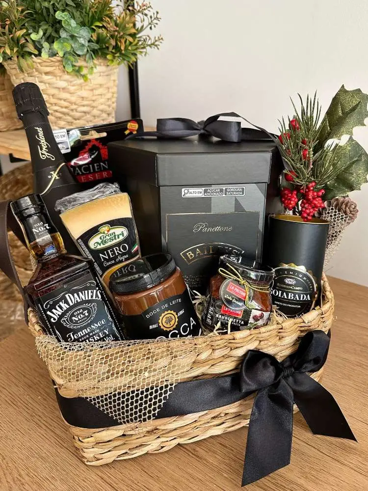 Cesta de Natal com itens pretos, como panetone, goiabada e whisky. 