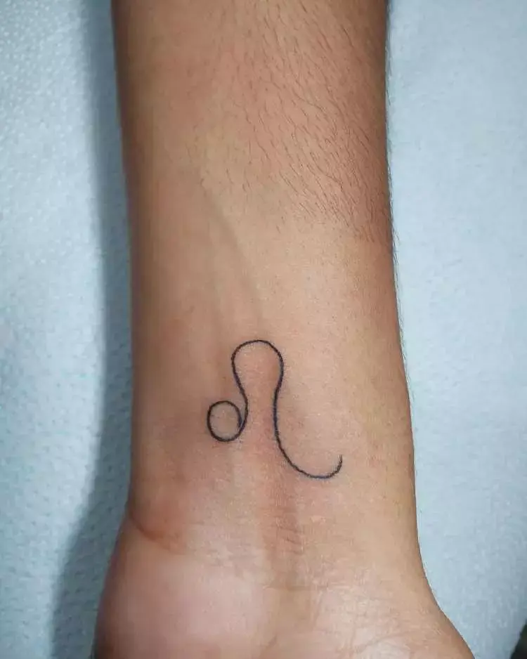Pessoa de pele clara com tatuagem fineline signo de leão no pulso 