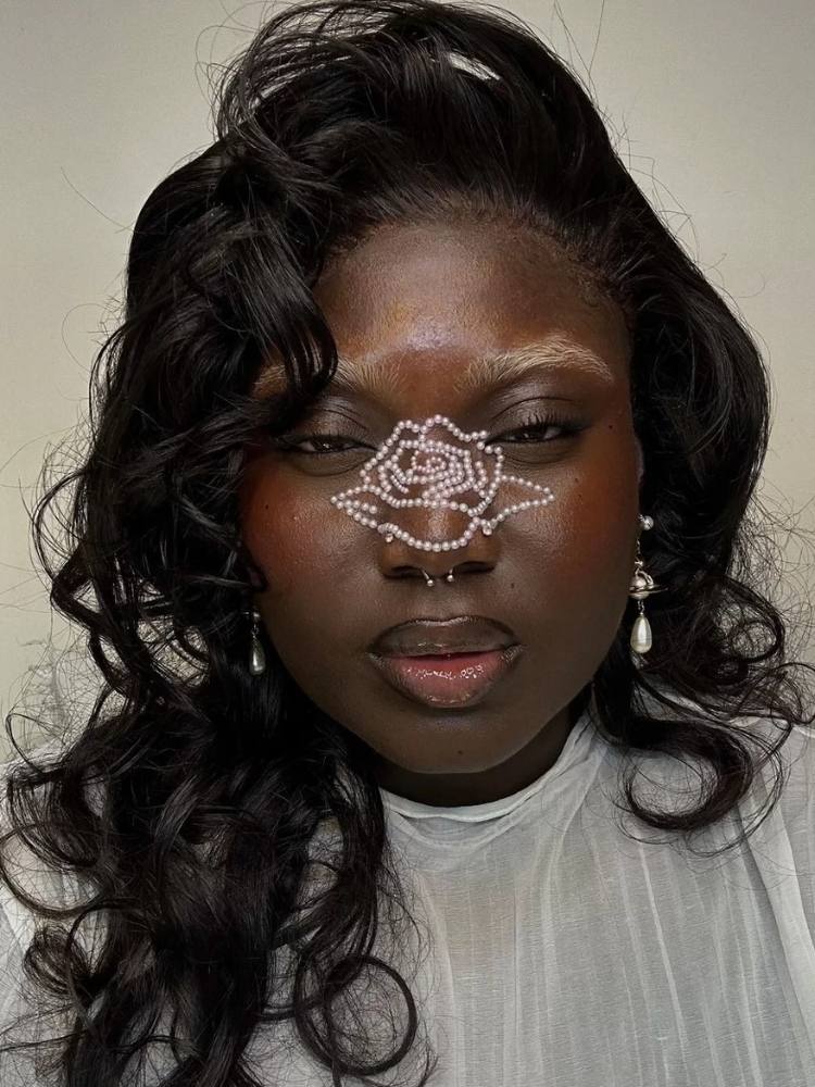 Mulher de pele negra com flor de strass no nariz 