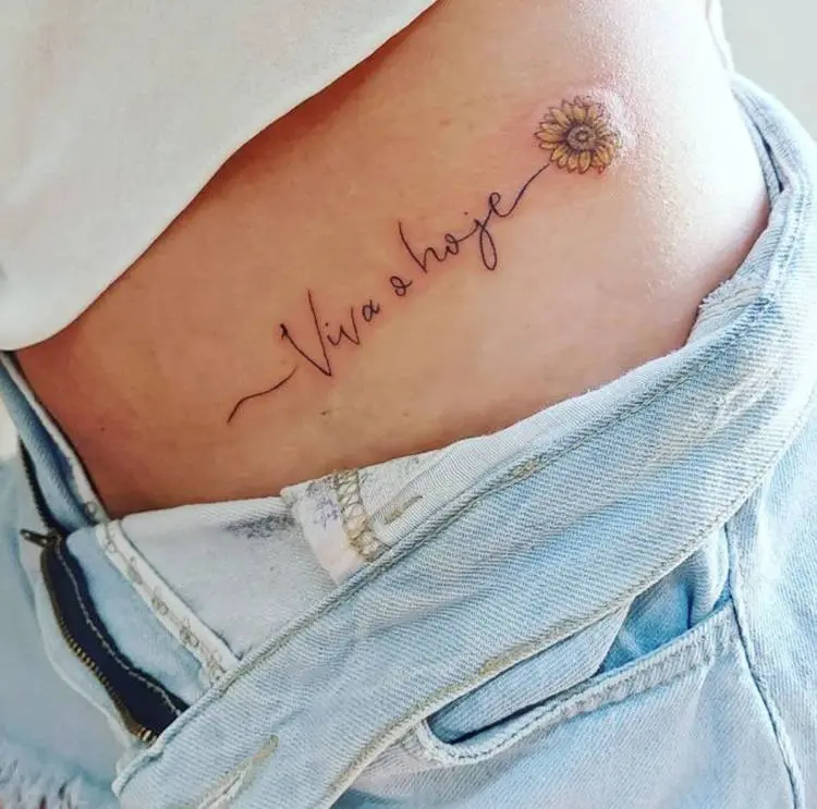 Tatuagem na cintura de flor e frase