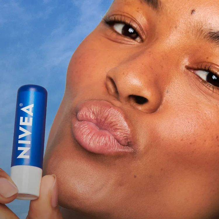 Mulher de pele negra com lábios hidratados segurando bastão Original Care da Nivea