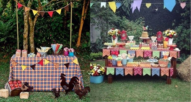 A imagem representa uma decoração de festa junina colorida ao ar livre. Contém mesa com comidas como bolo e doce, além de enfeites como bandeirinha e toalha xadrez