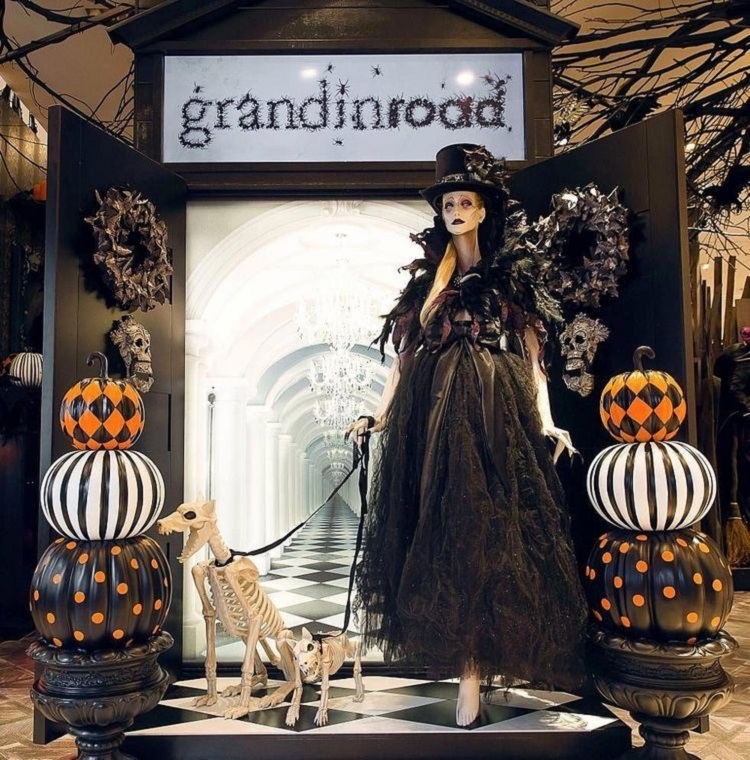 Vitrine decorada para o Halloween, com abóboras, cachorros em esqueleto, caveiras e manequim vestido de bruxa
