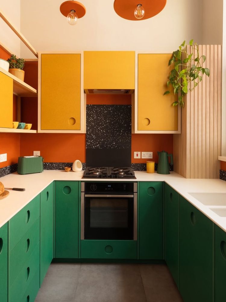Cozinha com parede terracota, armários amarelos e verdes escuros 