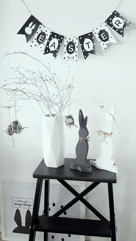 Decoração de Páscoa com coelhos, árvore e bandeirinhas.