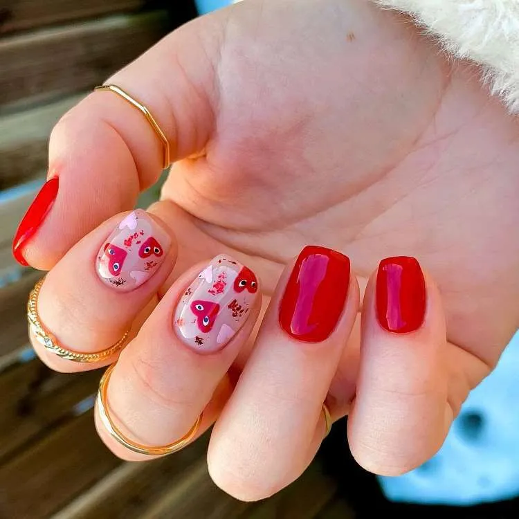 Unhas vermelhas decoradas com corações de olhos