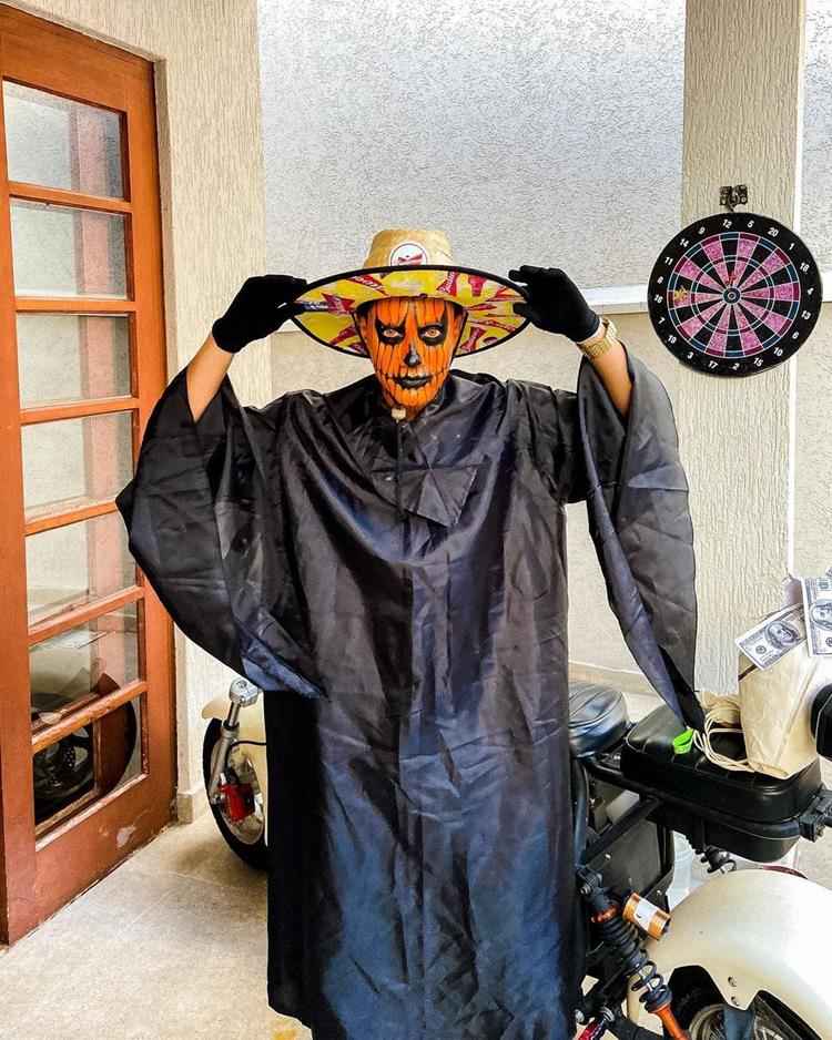 homem com capa preta e maquiagem de abóbora