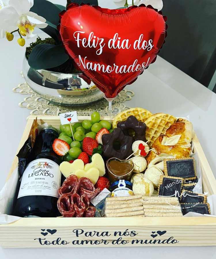 Cesta de madeira com bebida, frutas, guloseimas