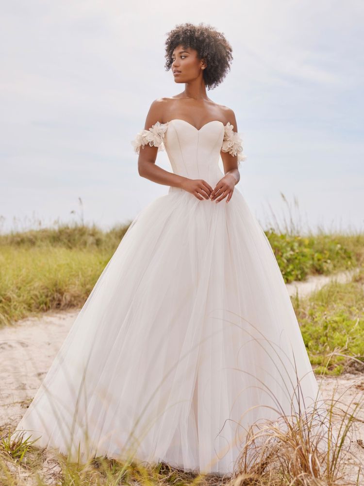 Mulher de pele negra usando vestido de noiva minimalista sem alça e detalhe de flores 3d na manga 