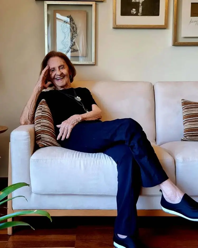 Laura Cardoso sorrindo sentada em sofá.
