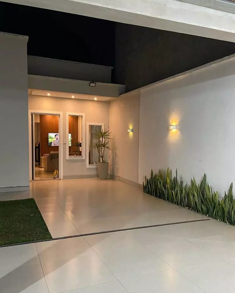 Imagem de fachada de casa simples, com vaso de planta, chão de piso e jardim de espadas de são jorge