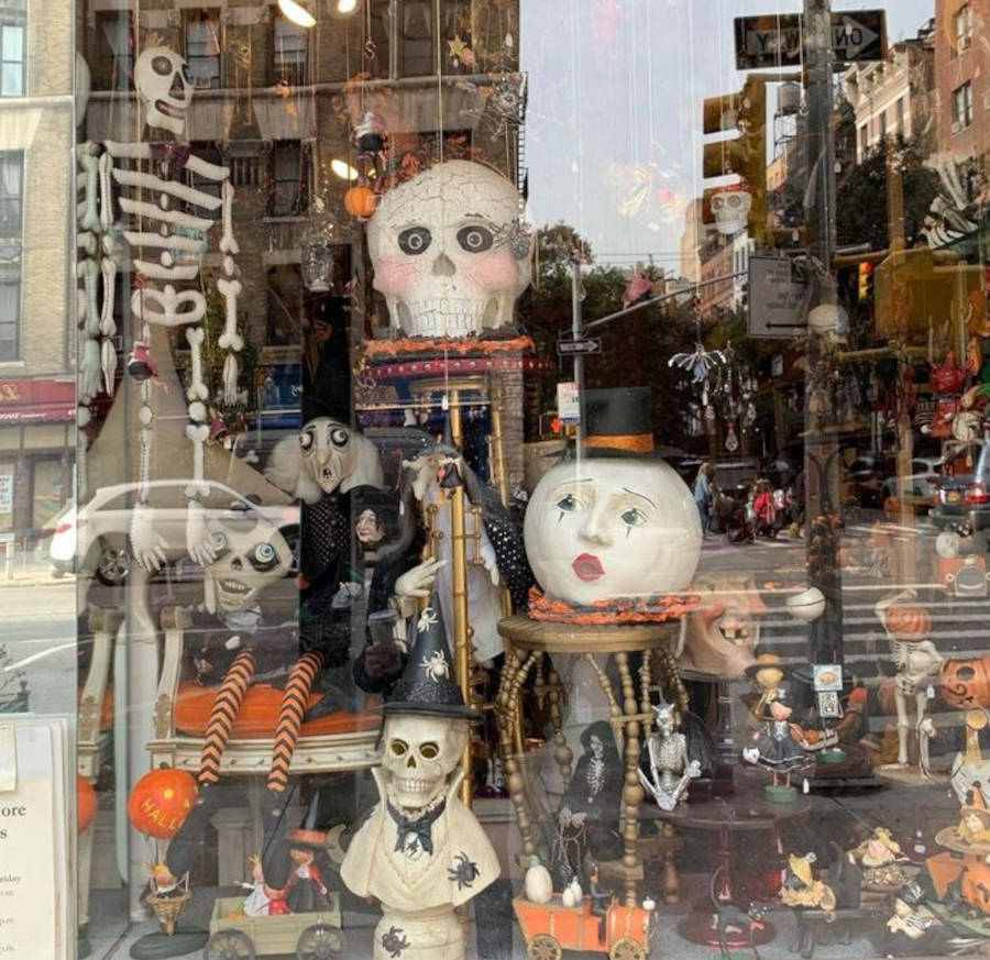 Foto de uma vitrine de Halloween com muitos elementos, como bruxa, caveira, abóbora, aranha, entre outros