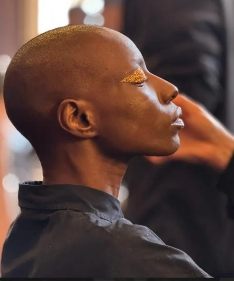 Modelo negro recebendo maquiagem amarela nos olhos