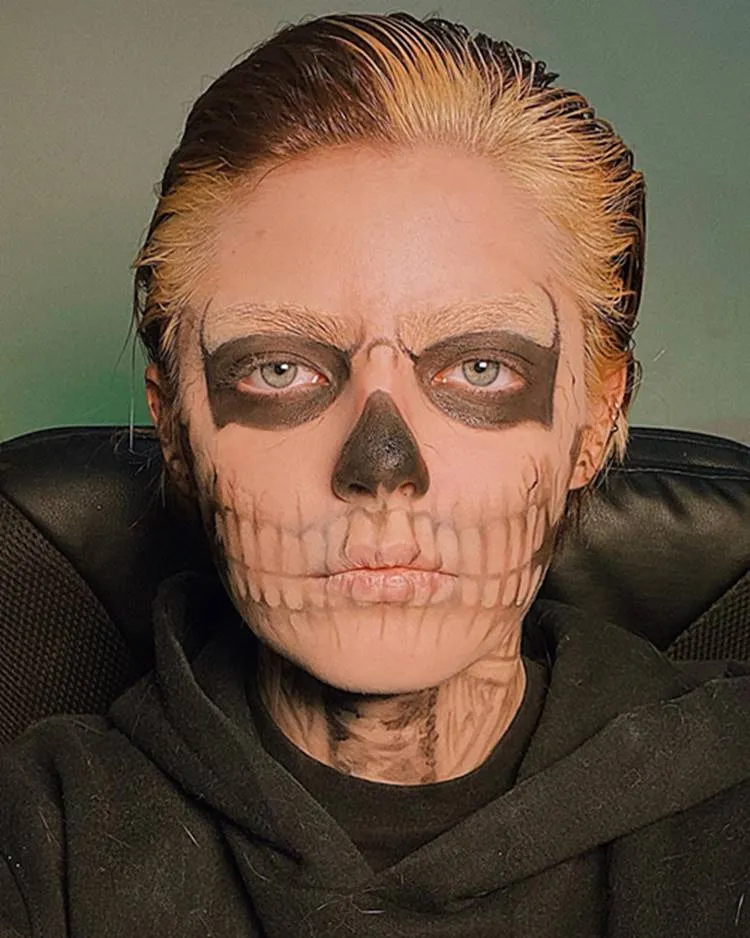 Homem de pele clara maquiado de caveira para o Halloween