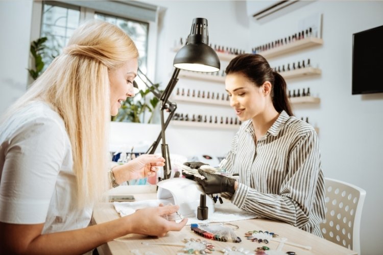 Foto de manicure fazendo as unhas de cliente
