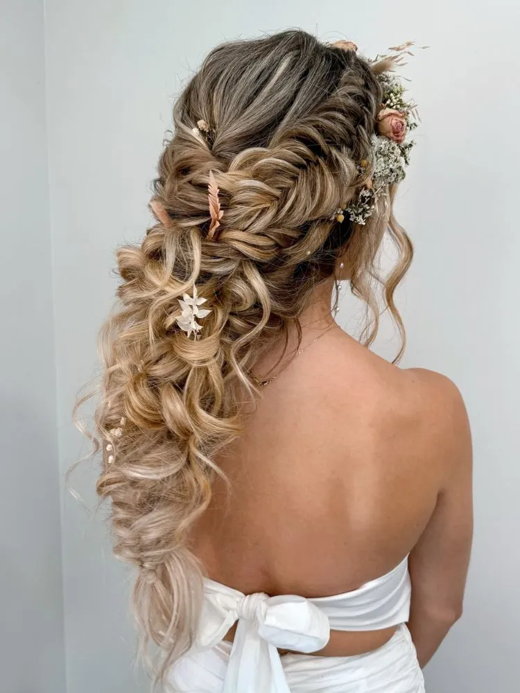 Mulher loira de pele clara de costas com trança fada com flores boho
