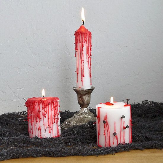 Velas branca e vermelha com prego para decorar no Dia das Bruxas