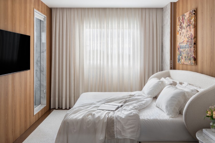 Quarto com cama de casal, cabeceira estofada, paredes de madeira e cortina 
