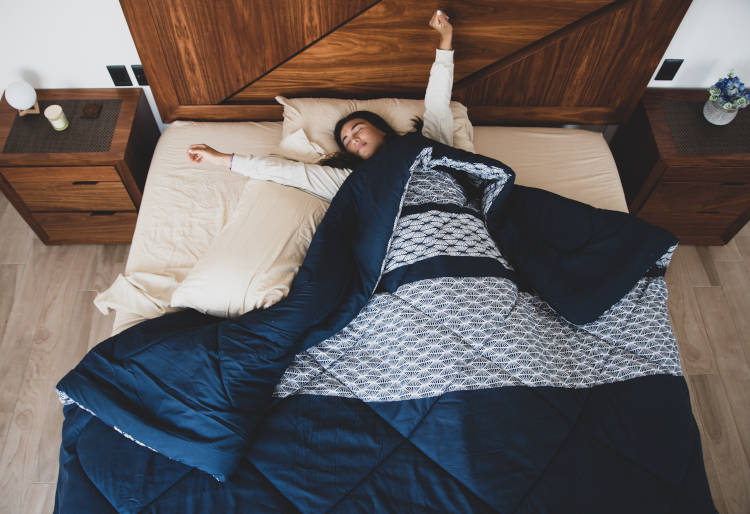 Mulher acordando em cama de casal.