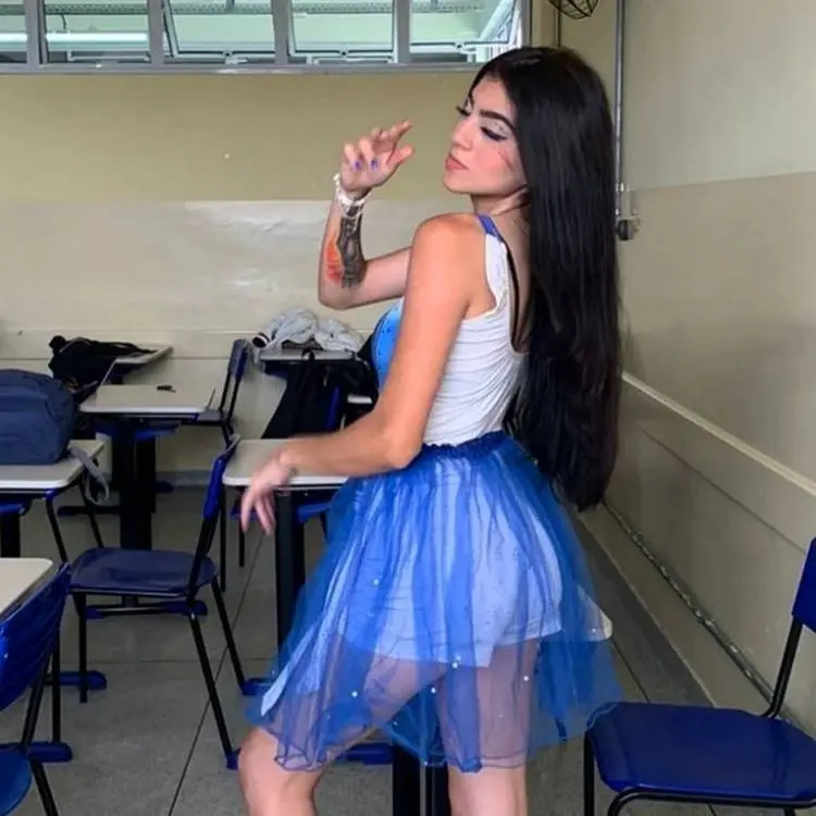 Mulher de pele clara com blusa branca e azul e saia de tule azul com shorts por baixo