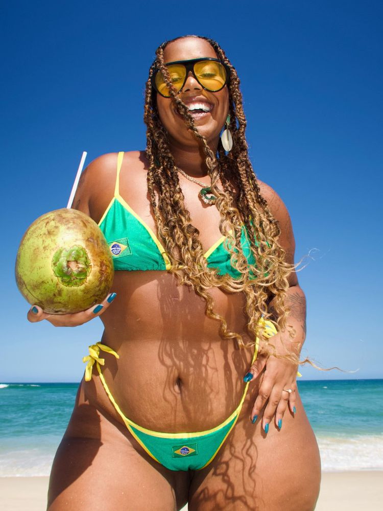 Mari Lobo de biquini do Brasil e óculos com lente amarela, segurando coco