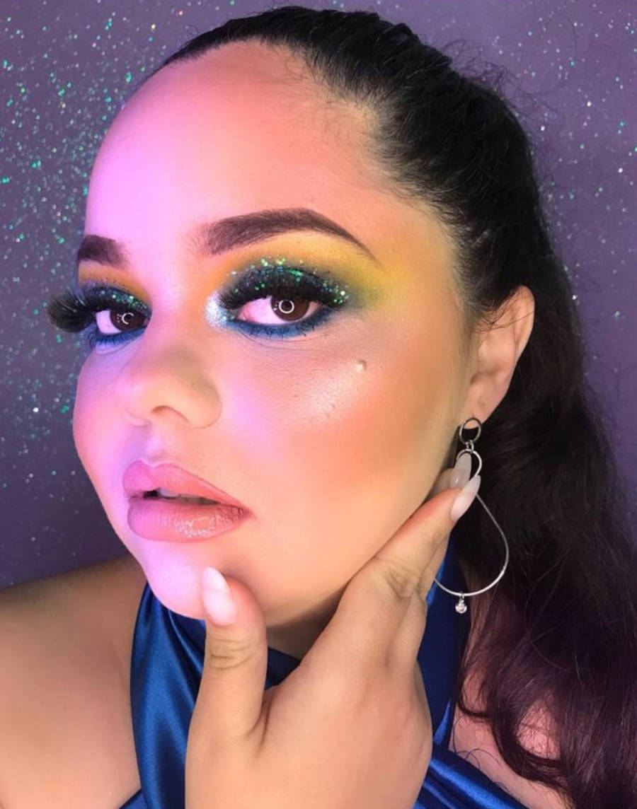 Foto de mulher com maquiagem esfumaçada em verde, amarela, azul e glitter para a copa do mundo