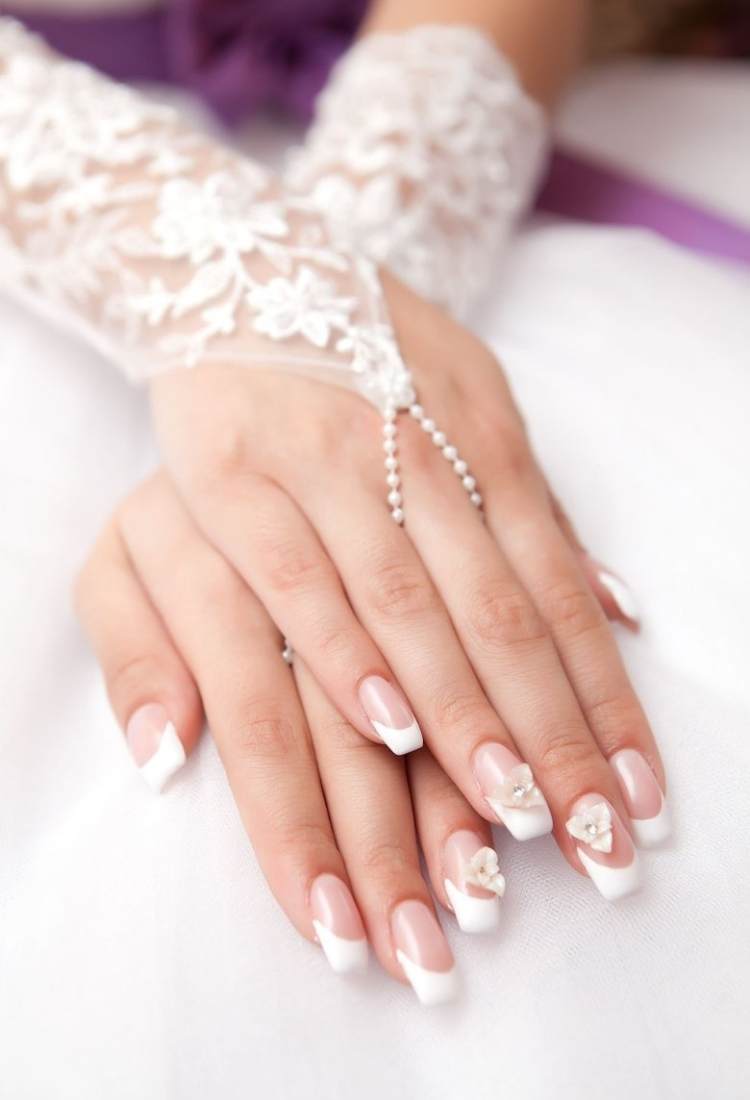 Mulher de pele clara usando vestido de noiva, luva e unhas quadradas com francesinha grossa, além de flores 3d