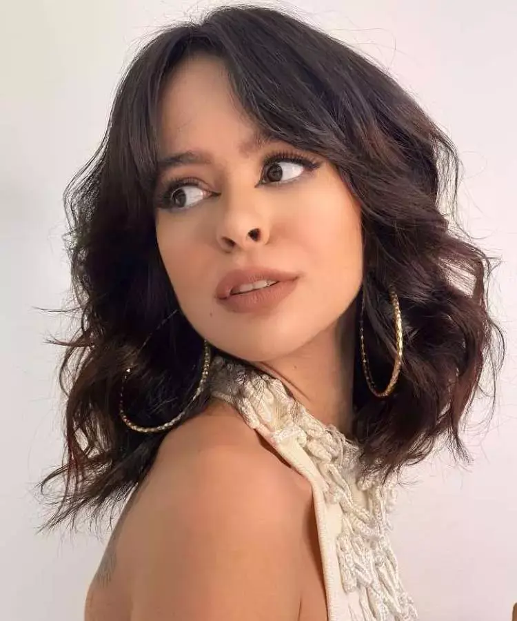 Mulher com corte de cabelo médio onduladocastanho franja estilo anos 70