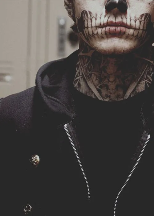 Zoom em homem com maquiagem de caveira e pescoço tatuado