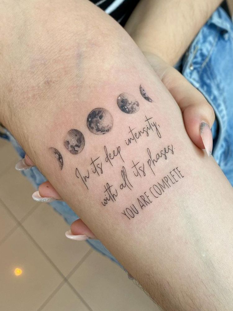 Foto de tatuagem das fases da lua, com frase em inglês embaixo.