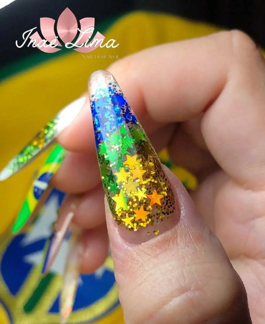 Imagem de mão decoradas com esmalte. Cores usadas, verde, amarelo, azul e branco. Glitter de estrela dourado, verde e azul + glitter normal dourado, verde e azul.