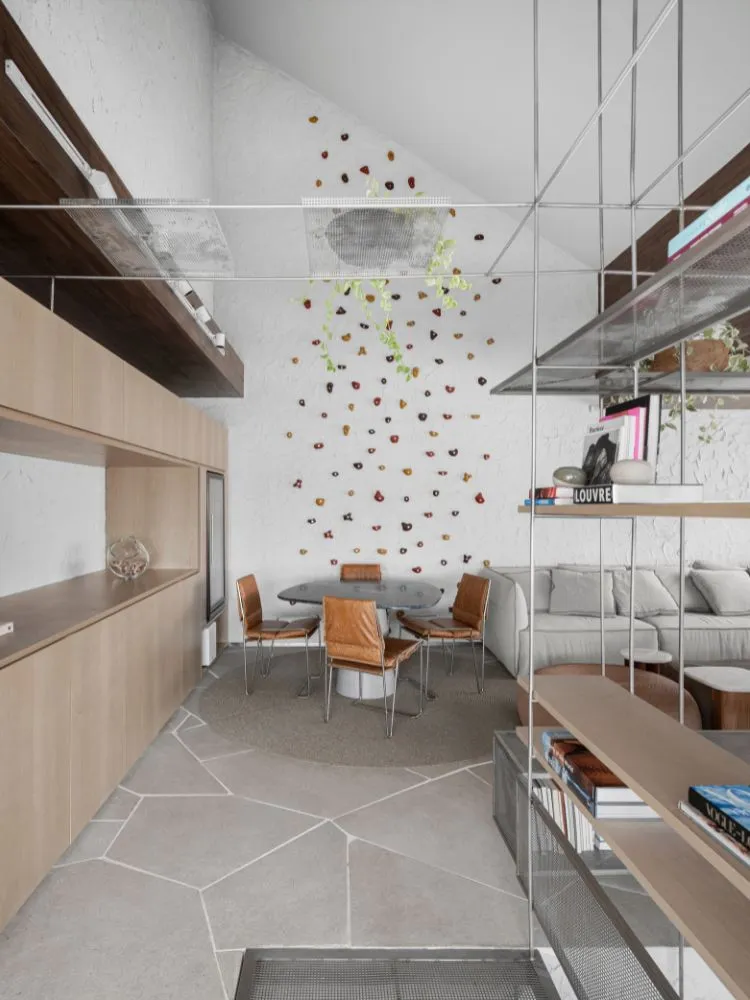 Apartamento decorado com parede de escalada em tons terrosos na parede da sala de jantar